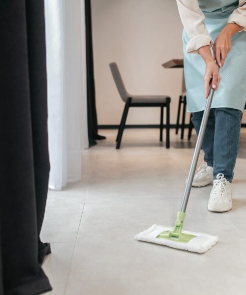 reinigung-der-kueche-eine-junge-frau-in-schuerze-die-den-boden-in-der-kueche-putzt_259150-59703